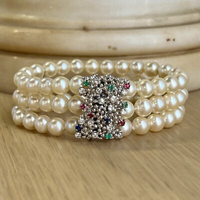 Bracelet 3 rangs en perles de culture. Fermoir en or blanc, saphirs, rubis, émeraudes et diamants