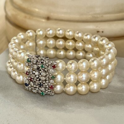Bracelet 3 rangs en perles de culture. Fermoir en or blanc, saphirs, rubis, émeraudes et diamants