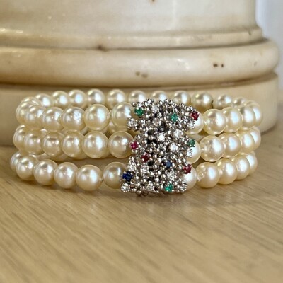 Bracelet 3 rangs en perles de culture. Fermoir en or blanc, saphirs, rubis, émeraudes et diamants