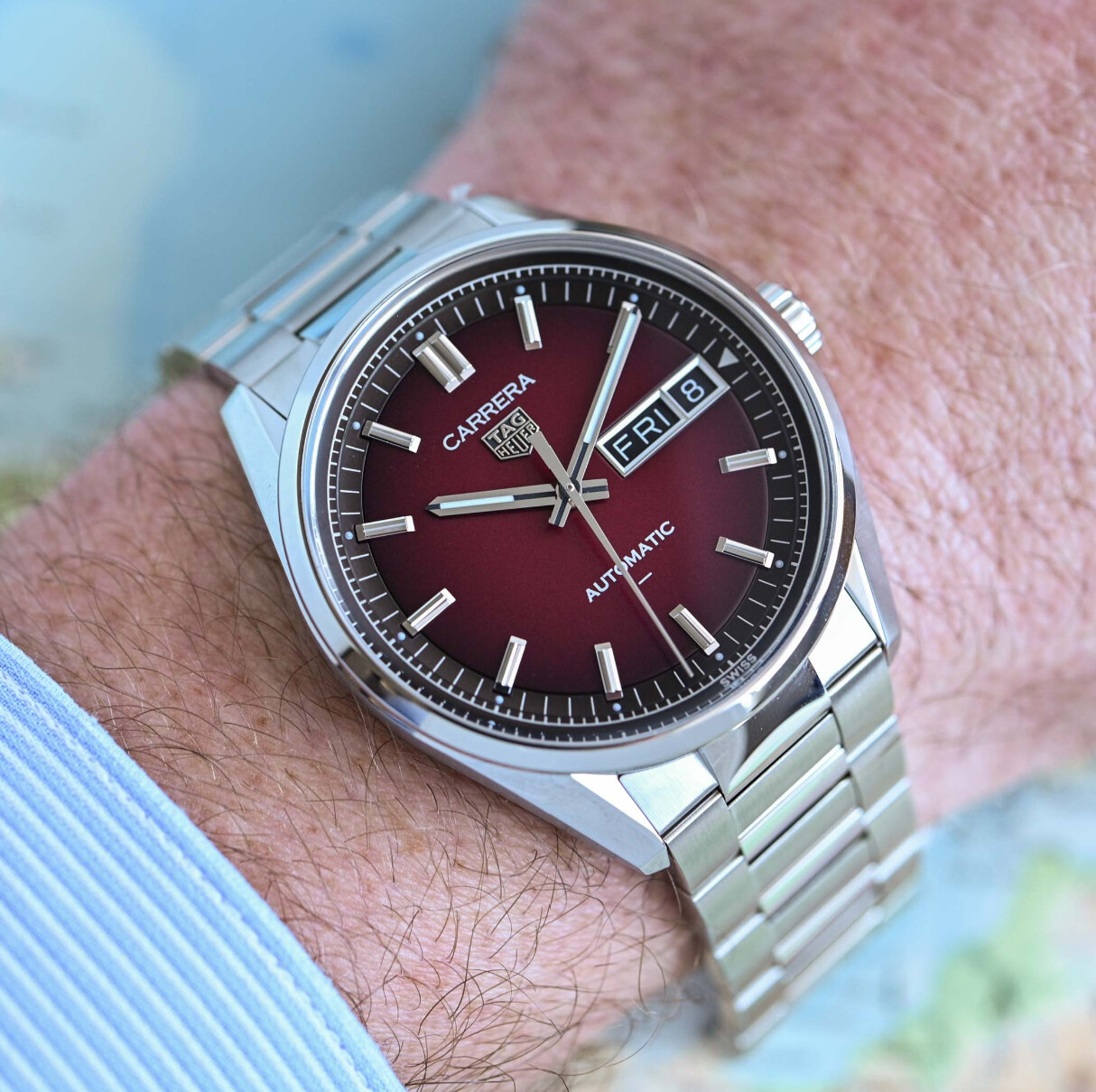 Montre TAG Heuer Carrera Day Date portée au poignet avec une carte en arrière-plan
