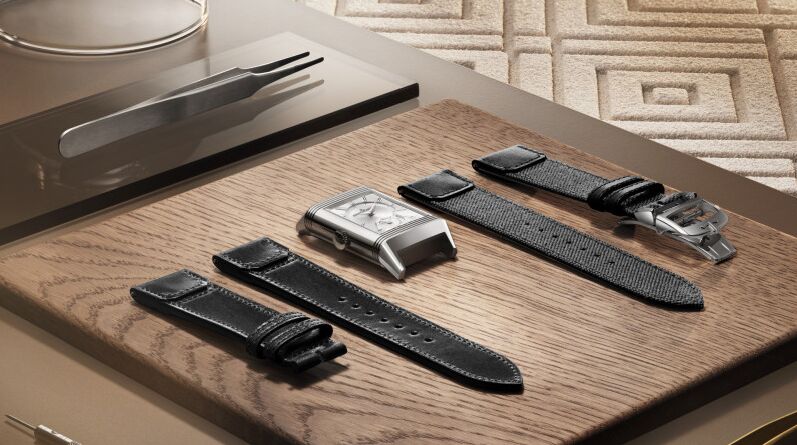 Montre Jaeger-LeCoultre Reverso Tribute Duoface Small Seconds démontée en trois parties avec un second bracelet, le tout déposé sur du bois