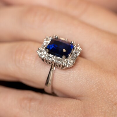 Bague en or blanc avec saphir bleu taille émeraude et entourage de diamants