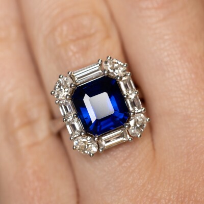 Bague en or blanc avec saphir bleu taille émeraude et entourage de diamants
