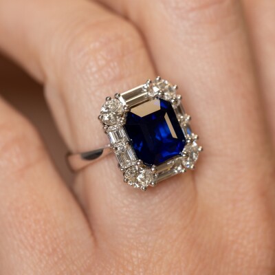 Bague en or blanc avec saphir bleu taille émeraude et entourage de diamants