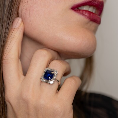 Bague en or blanc avec saphir bleu taille émeraude et entourage de diamants