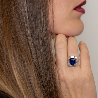 Bague en or blanc avec saphir bleu taille émeraude et entourage de diamants