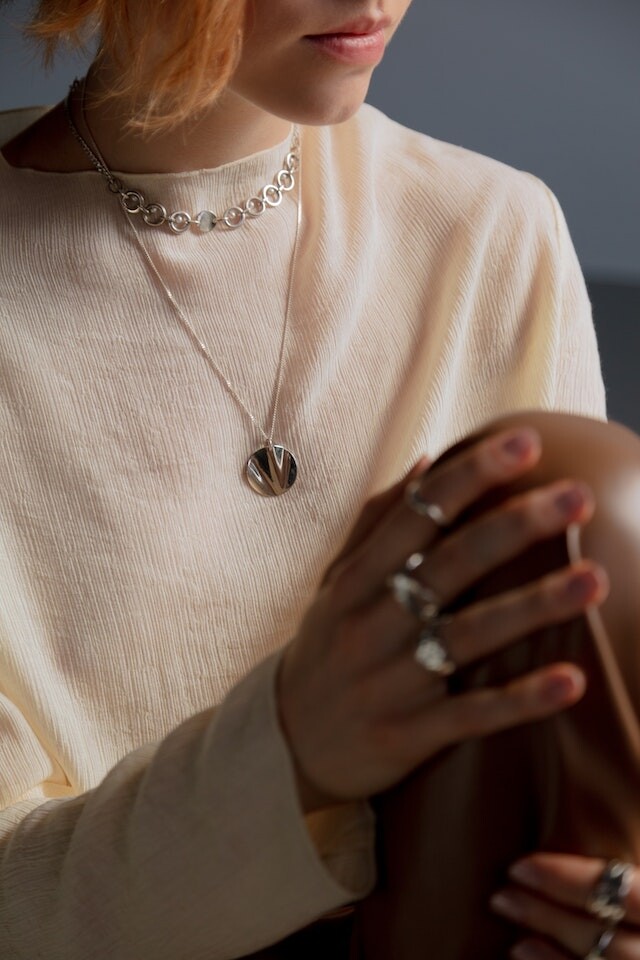 médaille en or blanc portée par une femme